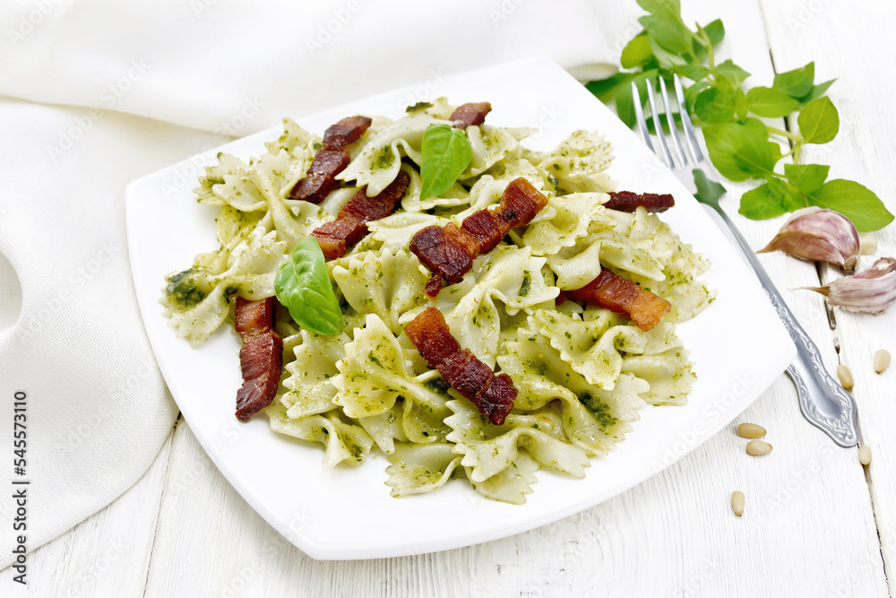 Farfalle with pesto and bacon in plate on light board
