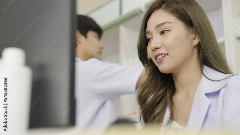 Happy Asian woman pharmacist in drugstore or pharmacy using computer Happy Asian woman pharmacist in drugstore or pharmacy using computer