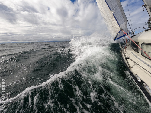 Sailboat fights storm and waves in open sea. Concept of travel, adventure, risk and adrenaline