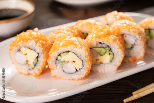 Sushi roll set with shrimp, flying fish reo, avocado and cucumber on a white plate. Japanese cuisine