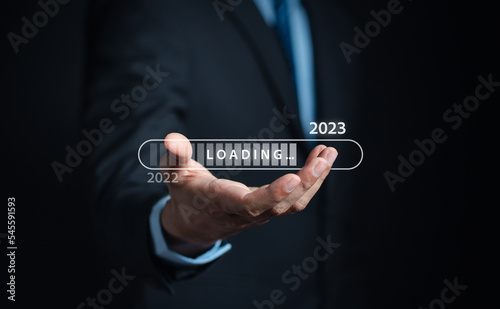 Businessman touching to virtual download bar and loading for New Year and changing year 2022 to 2023. start up planing business in next years concept...