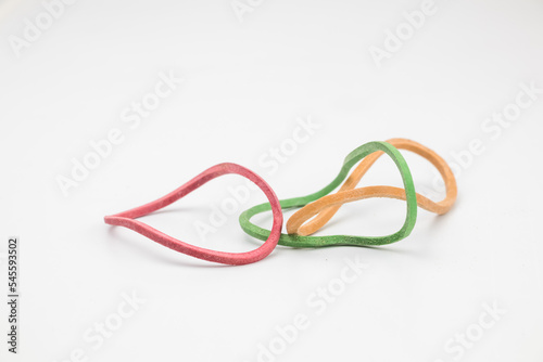 Three rubber bands in yellow, green and red in abstract shape on a white background.
