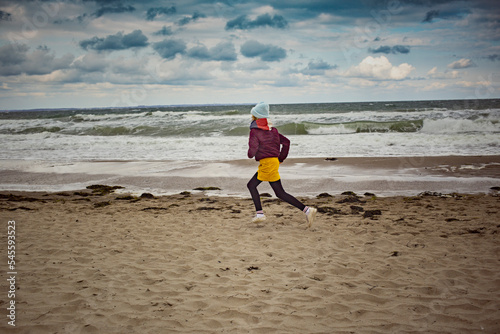 Girl running on a stormy cloudy day on the beach photo