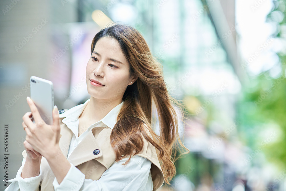 屋外でスマートフォンを手にする女性 屋外でスマートフォンを手にする女性