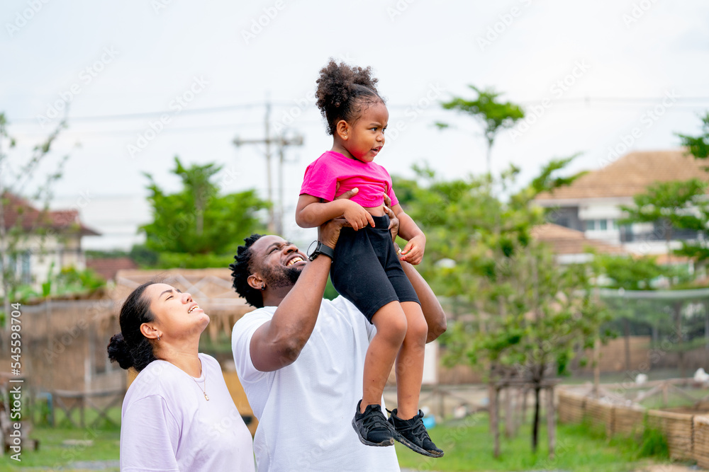 Obraz premium African American man hold and support his daughter up to get high view with fun together in public park.