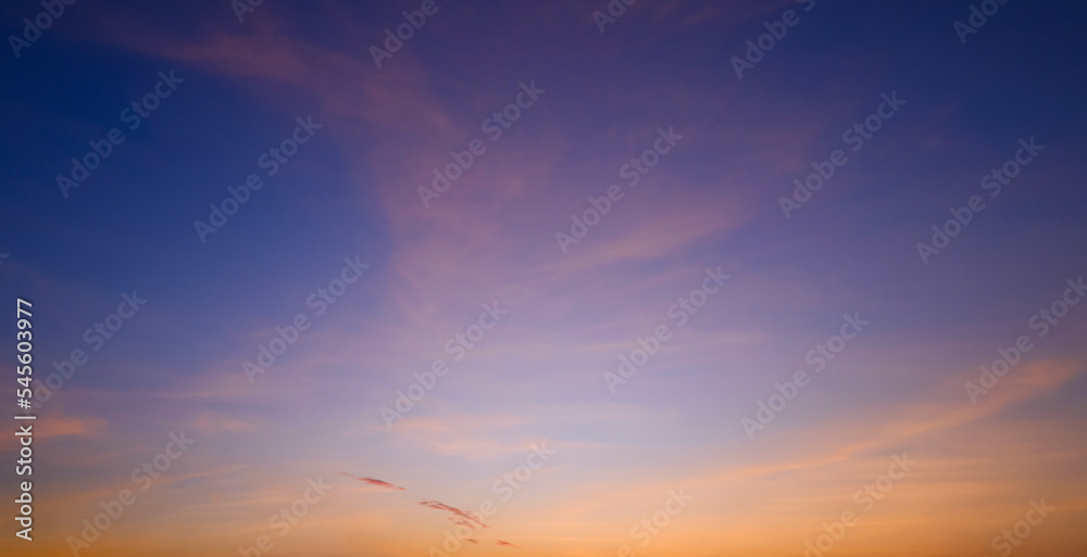 Sunset sky background with beautiful yellow sunlight clouds after sundown on blue twilight sky
