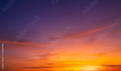 Colorful dusk sky background after sundown with beautiful orange sunlight clouds on blue twilight sky in wide screen view