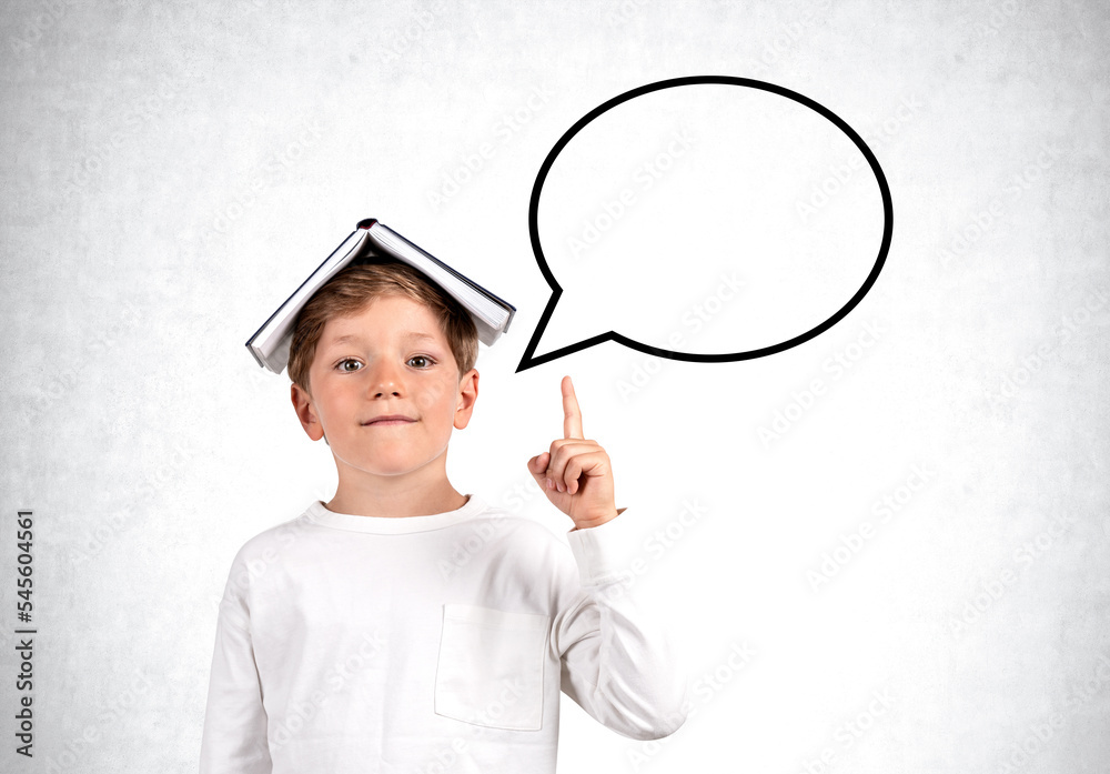 Child boy with finger pointing up, speech bubble on empty grey wall background Child boy with finger pointing up, speech bubble on empty grey wall background