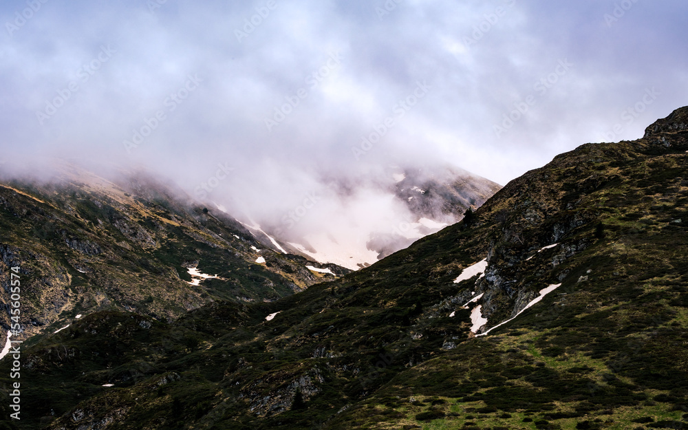 Clouds lingering on the peaks of the French Pyrenees mountains range near Ayes Lake on a moody day