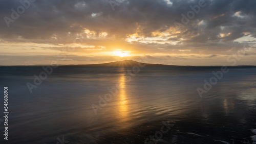 Sunrise over the top of Rangitoto Island. Milford Beach, Auckland. © Janice