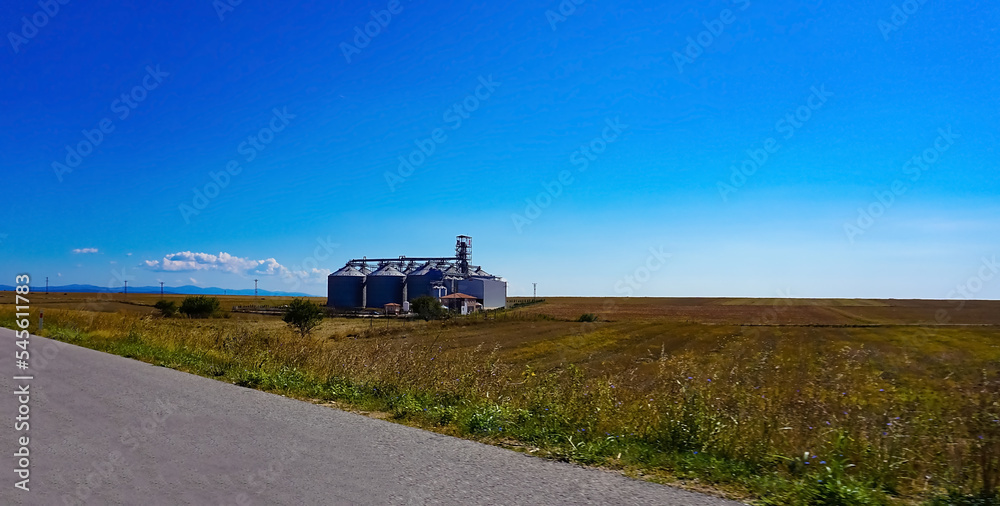Modern agricultural silos or grain elevator with blue sky on the background.