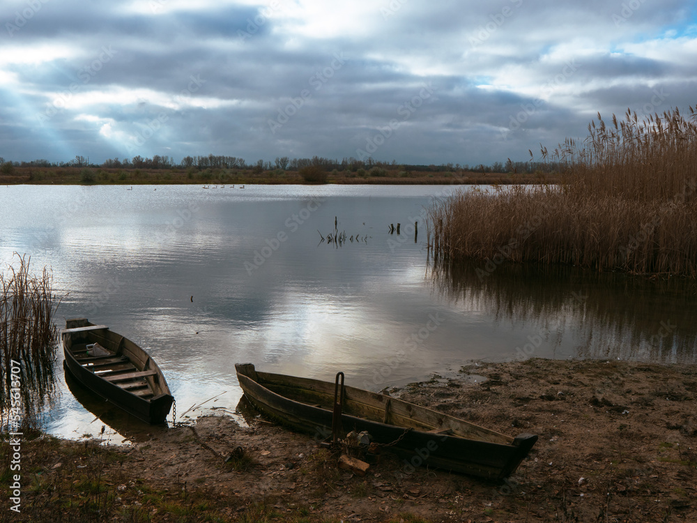 Obraz premium boats near the river bank at dawn. wooden boats on the water. clouds reflecting in the water of the river. canoe by the river.