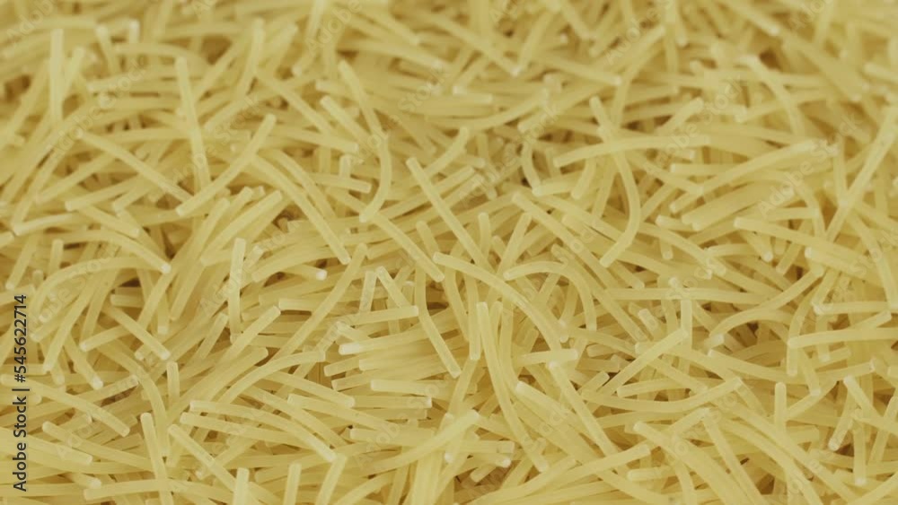 Small raw pasta is spinning on a turntable. View from above. Food background. Small raw pasta is spinning on a turntable. View from above. Food background.