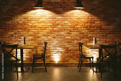 Restaurant dining tables against brick wall.