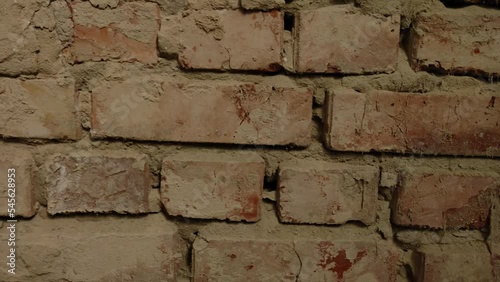Collapsing red brick wall abandoned building, close-up. Details bricks with cracks. Concept of the destruction of building in disrepair.
