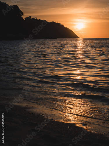 Scenic view of Sunset Beach, Koh Lipe Island. Dramatic sunset orange sky with sunlight reflection on sea water waves. Satun, Thailand.