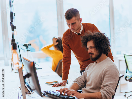 Two men discuss a project while looking at a computer monitor in a modern office