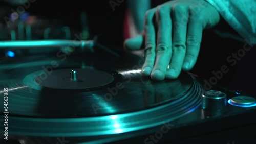 Hip hop dj in santa claus costume scratches vinyl record with music on party. Disc jockey plays set on Christmas celebration in night club photo