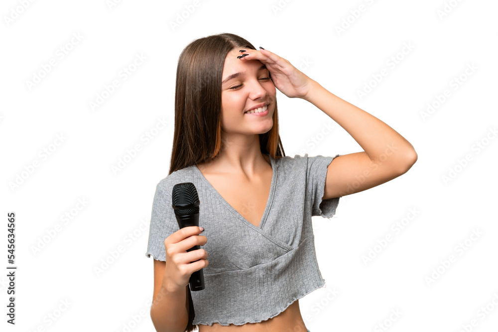 Teenager singer girl picking up a microphone over isolated background smiling a lot Teenager singer girl picking up a microphone over isolated background smiling a lot