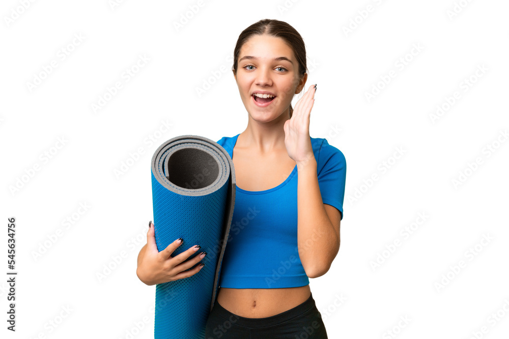 Teenager caucasian girl going to yoga classes while holding a mat over isolated background shouting with mouth wide open Teenager caucasian girl going to yoga classes while holding a mat over isolated background shouting with mouth wide open
