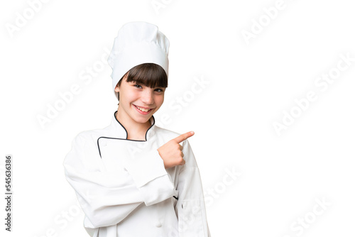 Little caucasian chef girl over isolated background pointing to the side to present a product