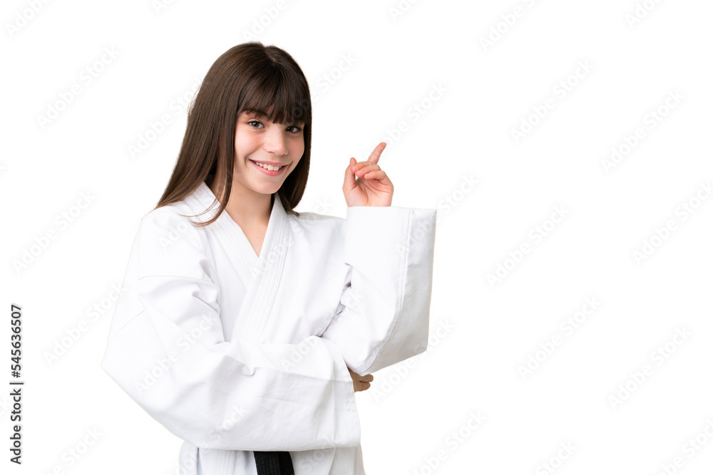 Little Caucasian girl doing karate over isolated background pointing finger to the side Little Caucasian girl doing karate over isolated background pointing finger to the side