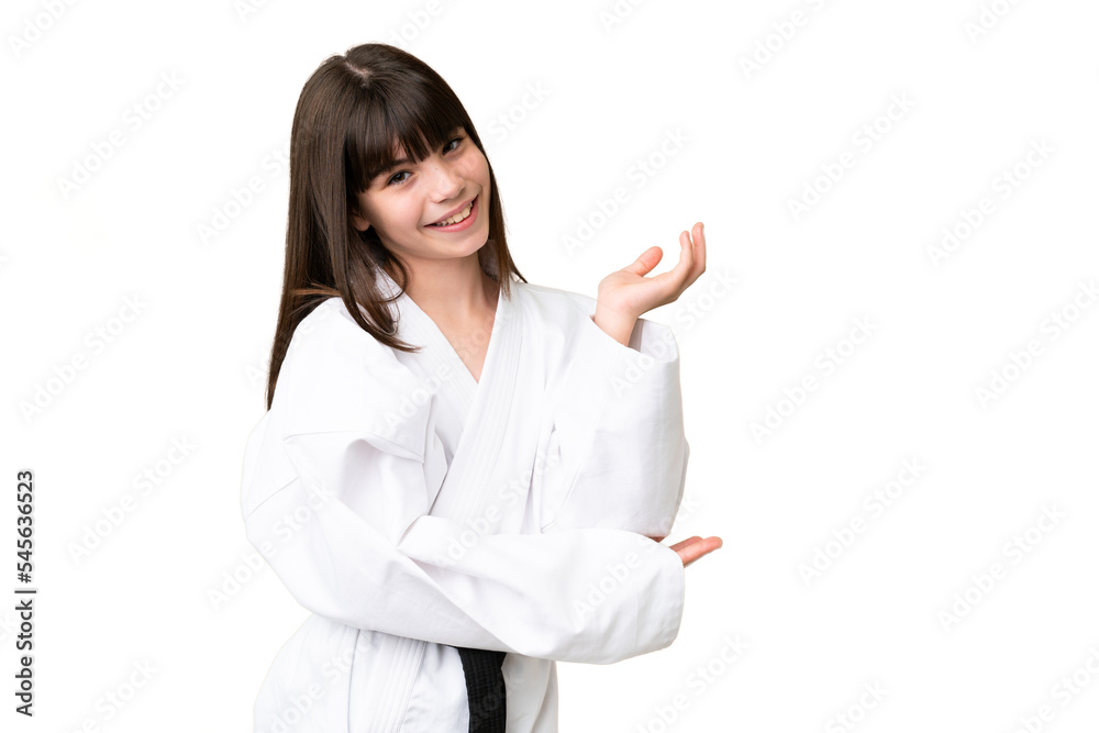 Little Caucasian girl doing karate over isolated background extending hands to the side for inviting to come Little Caucasian girl doing karate over isolated background extending hands to the side for inviting to come