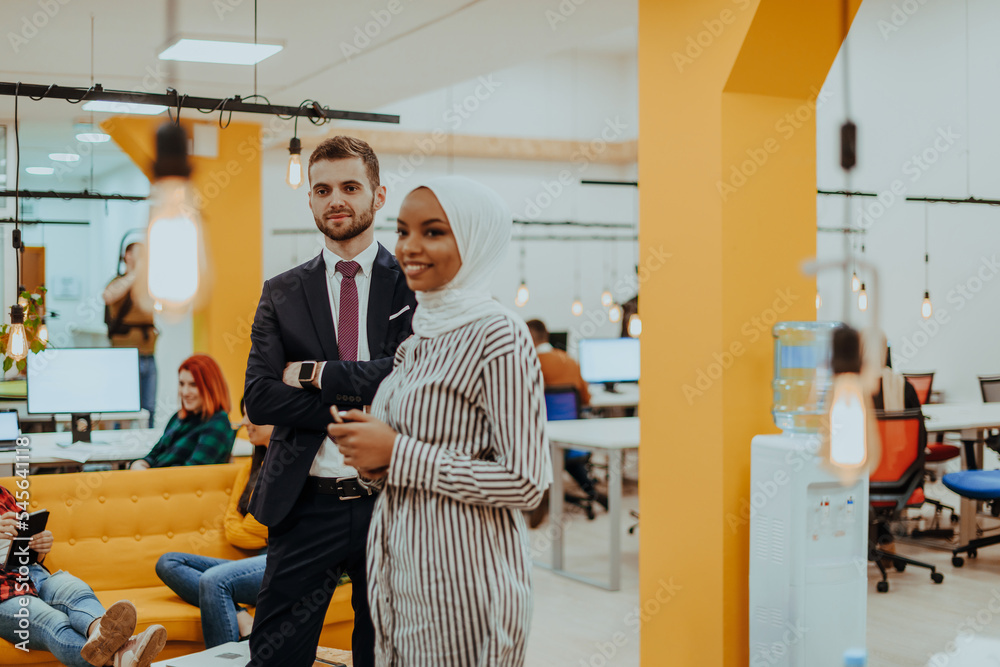 Fototapeta premium Portrait of a formal businessman and young African American businesswoman posing with their team in a modern startup office. Marketing concept. Multi-ethnic society.