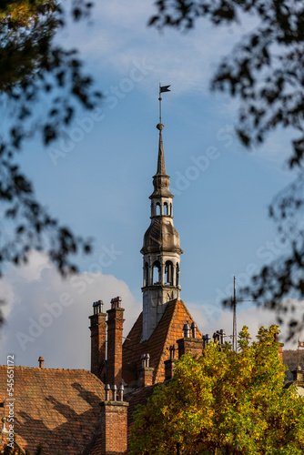 Detail of a old building with a big tower with vane on the roof on a sunny day on a blue sky background. West Ukraine