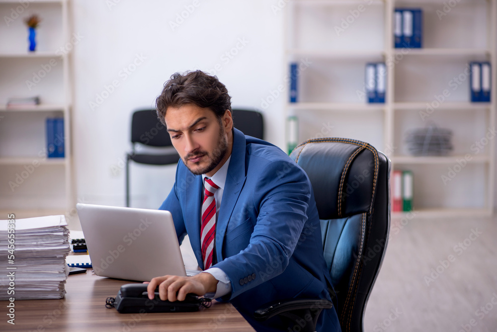 Young male employee and too much work in the office Young male employee and too much work in the office