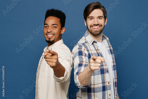 Side view young two friends happy men wear white casual shirt together point index finger camera on you motivating encourage isolated plain dark royal navy blue background People lifestyle concept.