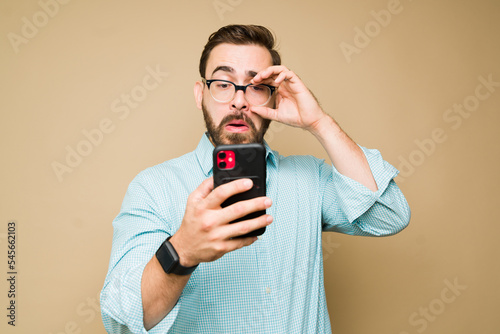 Man in his 30s trying to use his smartphone with eyesight problems