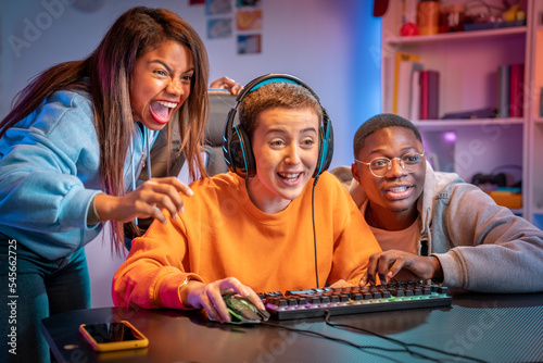 Excited gamers friends playing video games at home laughing while watching how is playing their friend