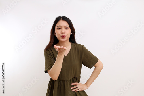 Beautiful young asian woman standing while blows or sending her kiss to camera. Isolated on white background