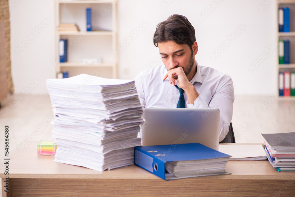 Young businessman employee unhappy with excessive work in the office Young businessman employee unhappy with excessive work in the office