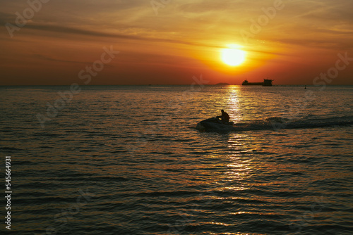 Driving jet ski on the sea at evening, silhouettes image