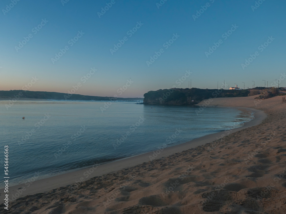 Blue hour sunrise view of Praia da Franquia sand beach at Vila Nova de Milfontes with Mira river and green vegetation.