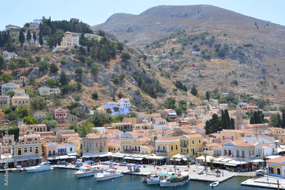 greek island Symi with boats, multicolored buildings and hills view from top