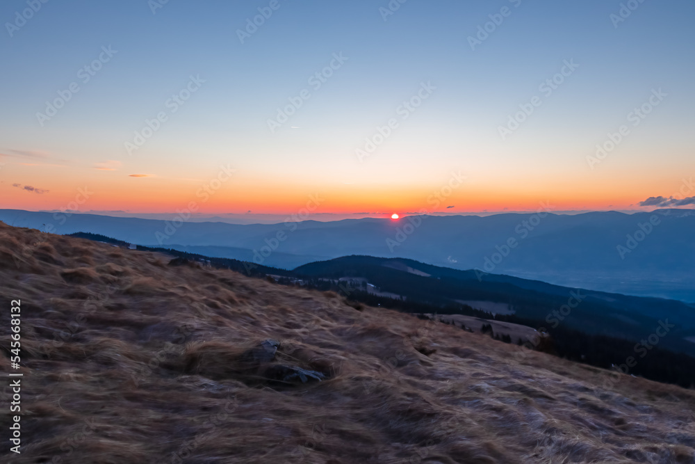 Scenic view during sunrise from mountain peak Zingerle Kreuz, Saualpe, Lavanttal Alps, Carinthia, Austria, Europe. Hiking trail Wolfsberg. Clouds in warm red colors and soft sky creating calm vibes