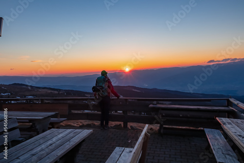 Silhouette of happy woman enjoying a beautiful sunset on mountain peak Ladinger Spitz, Saualpe, Lavanttal Alps, Carinthia, Austria, Europe. Warm atmosphere, inspiration, goal seeking concept © Chris