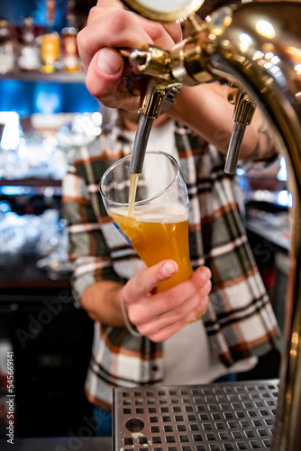 bartender s hands pouring craft beer from a tap into a glass in bar