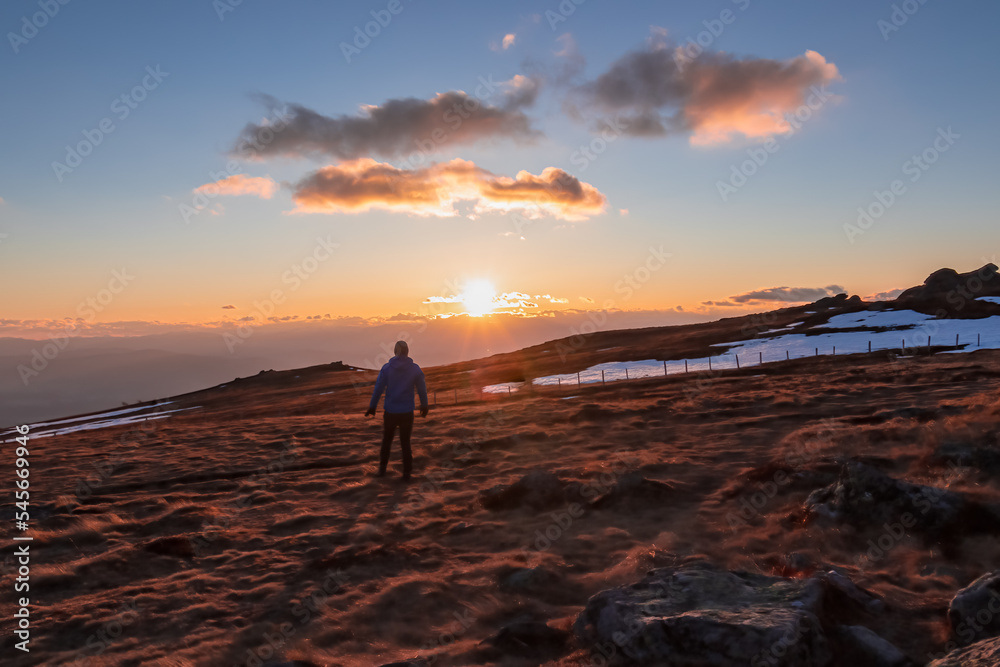 Silhouette of happy man enjoying a beautiful sunset on mountain peak Ladinger Spitz, Saualpe, Lavanttal Alps, Carinthia, Austria, Europe. Warm atmosphere, inspiration, goal seeking concept