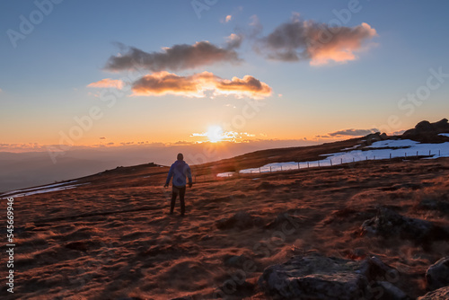 Silhouette of happy man enjoying a beautiful sunset on mountain peak Ladinger Spitz, Saualpe, Lavanttal Alps, Carinthia, Austria, Europe. Warm atmosphere, inspiration, goal seeking concept