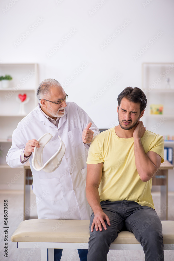 Young male neck injured patient visiting old male doctor Young male neck injured patient visiting old male doctor