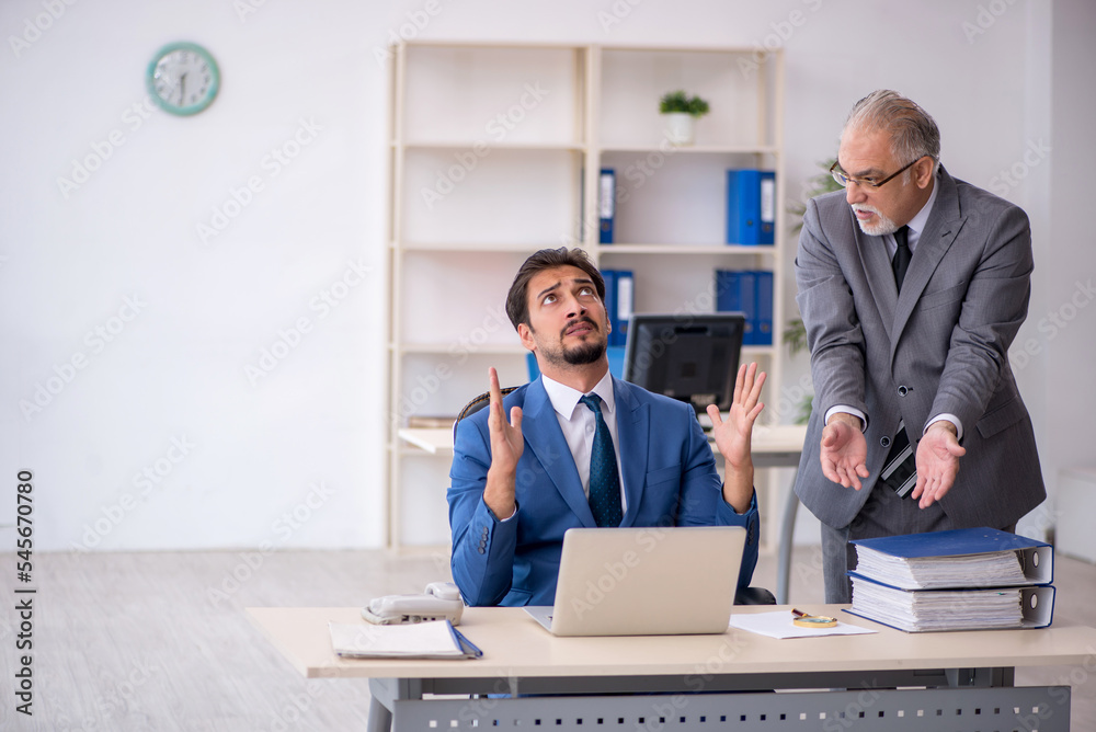 Old male boss and young male employee working in the office Old male boss and young male employee working in the office