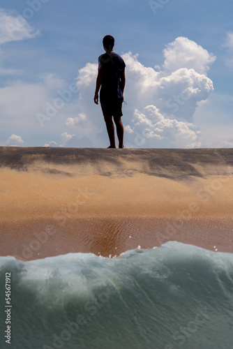 A relaxed young man in a swimsuit looking at the clouds on the shore of the beach