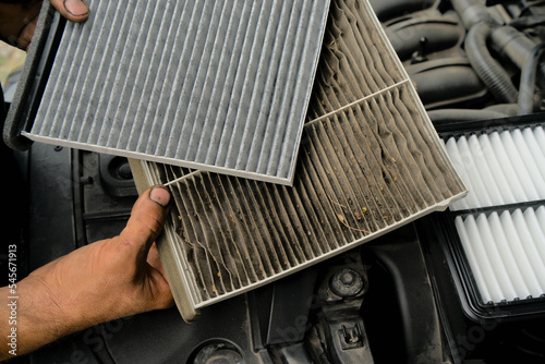 A new car air filter and an old one with garbage in the hands of a man. Comparison and preventive replacement in the car.