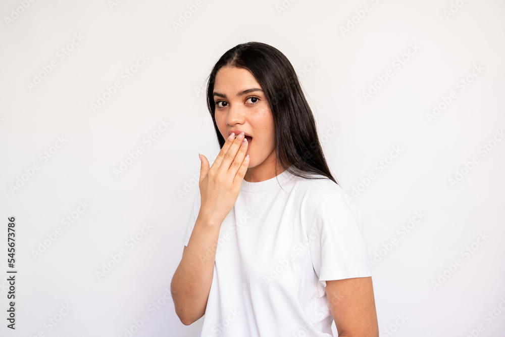 Portrait of shocked young woman covering mouth with hand. Caucasian lady wearing white T-shirt looking at camera in astonishment over white background. Surprise and shame concept Portrait of shocked young woman covering mouth with hand. Caucasian lady wearing white T-shirt looking at camera in astonishment over white background. Surprise and shame concept
