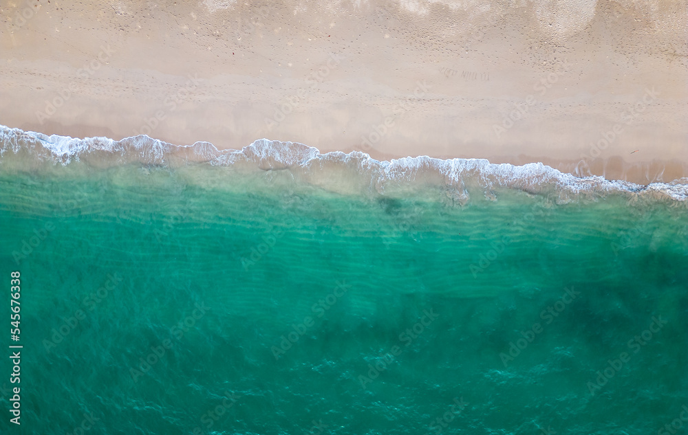 Aerial drone view (top down) to sea waves and white sand. Turquoise blue water, tropical theme. Concept of relaxation in pure nature.