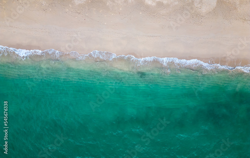 Aerial drone view (top down) to sea waves and white sand. Turquoise blue water, tropical theme. Concept of relaxation in pure nature.